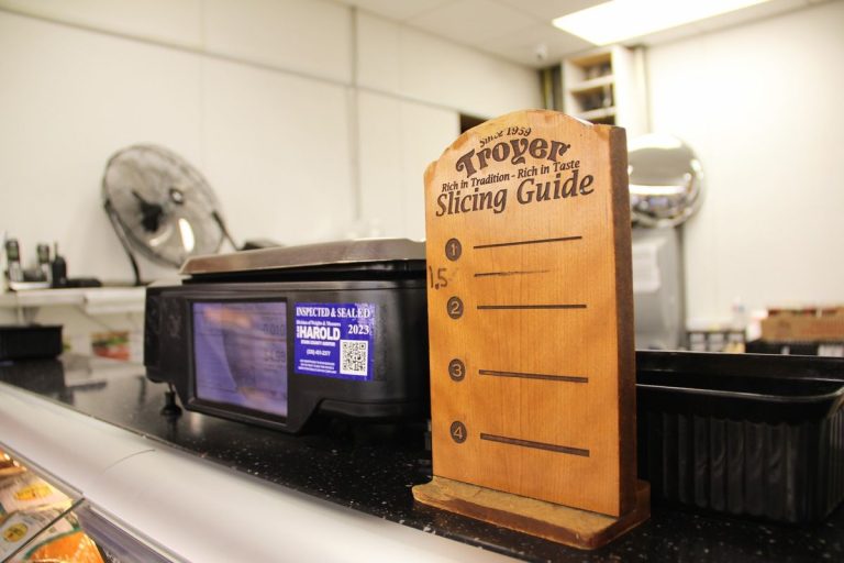 A wooden deli slicing guide next to a scale