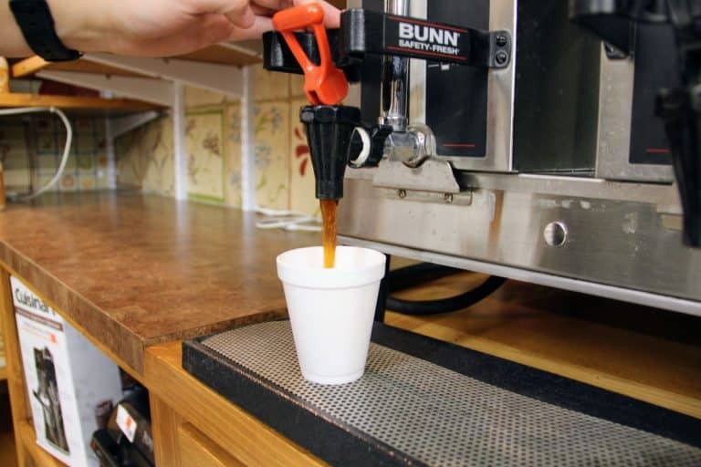 Coffee pouring out of machine into a cup