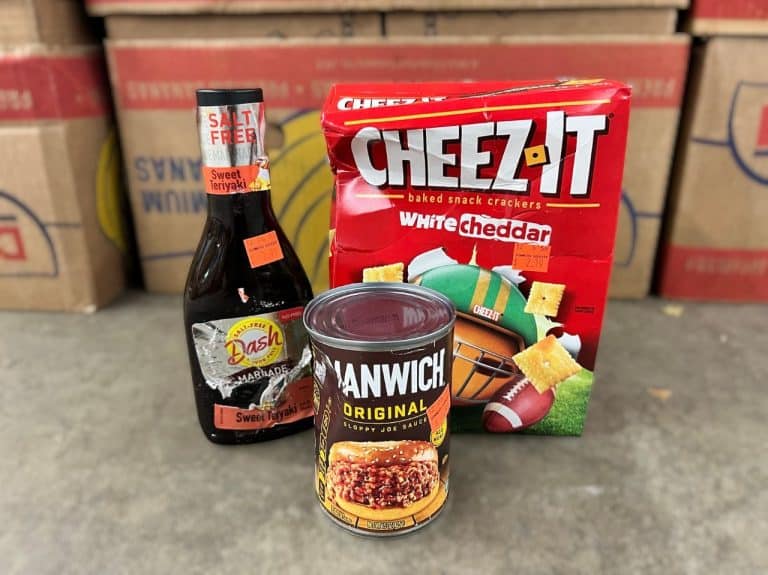 A dented can, bent cheez-it box, and sauce bottle with torn label